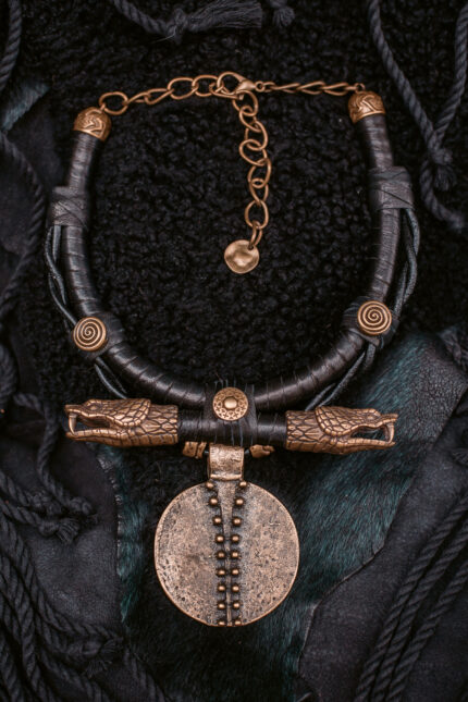 Quetzin Necklace: Tribal-inspired pendant with leather tubes, tribal medallion, and brass snake heads. Primal elegance and ancient symbolism.