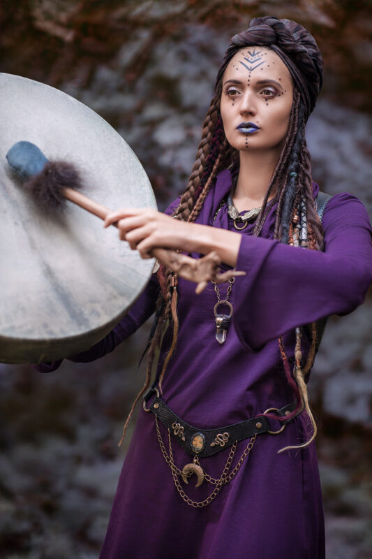 A black leather waist belt featuring a labradorite cabochon as the centerpiece. The belt is adorned with brass snakes, chains, and crescent moon charms, creating an edgy yet powerful statement piece.